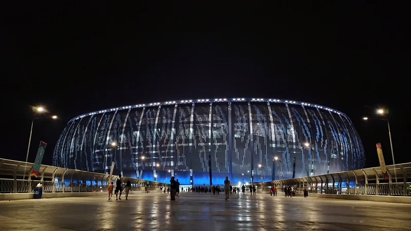 Jakarta International Stadium pada malam hari dengan pencahayaan biru